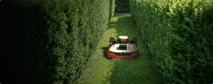 Kress EyePilot robotic mower mowing a grass path between tall clipped hedges
