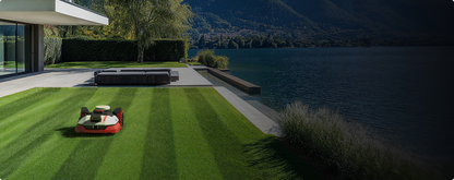 Kress EyePilot robotic mower creating lawn stripes on a lakeside lawn beside a modern home